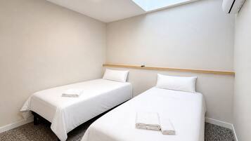 Una habitación de hotel con dos camas, un tragaluz y un equipo de aire acondicionado.