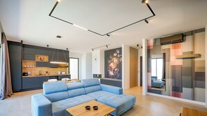 En moderne stue med en modulsofa, et træsofabord og et køkkenområde med indbyggede apparater.