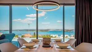 A dining table set for six with a view of the sea through large windows. - Villa View with breathtaking sea view, privacy, infinity pool, and jacuzzi (Ugrinić)