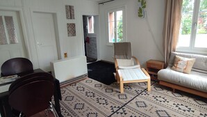 Una habitación con un sofá, una silla, una mesita, un radiador y una puerta.