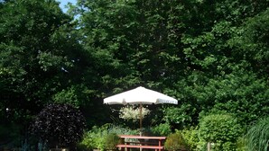 Ein Garten mit einer roten Bank und einem weißen Sonnenschirm.