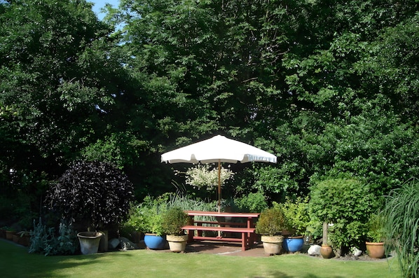 A garden with a red bench and a white umbrella. - Apartment '3 Dg' with Shared Garden and Wi-Fi (Cuxhaven)
