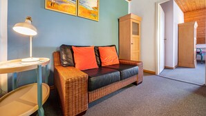 A room with a wicker sofa, a lamp, and two paintings on the wall. - Apartment '3 Dg' with Shared Garden and Wi-Fi (Cuxhaven)