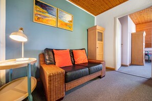 Ein Zimmer mit einem Korbsessel, einer Lampe und zwei Bildern an der Wand.