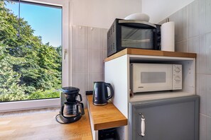 A compact kitchen with a coffee maker, a microwave, and a kettle on a wooden countertop. - Apartment '3 Dg' with Shared Garden and Wi-Fi (Cuxhaven)