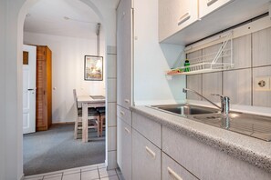 A modern kitchen with a granite countertop, stainless steel sink, and wooden cabinets. - Apartment '4 Dg' with Shared Garden and Wi-Fi (Cuxhaven)
