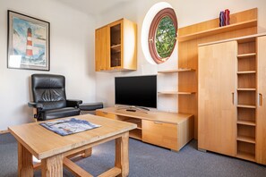 Una habitación con escritorio, silla, televisor y armario.