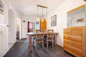 A dining area with a wooden table and chairs, a wooden dresser, and a clock on the wall. - Apartment '4 Dg' with Shared Garden and Wi-Fi (Cuxhaven)