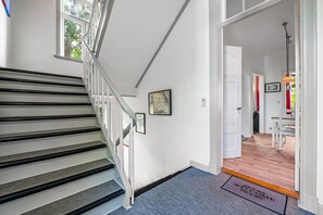 A staircase with a handrail and a landing with a doormat.