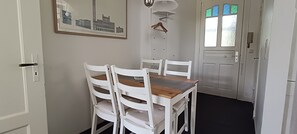 A dining area with a table and four chairs, a framed picture on the wall, and a door with stained glass windows.
