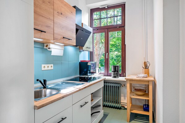 Una cocina moderna con estufa integrada, cafetera y ventana con vista a árboles.