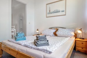 A neatly made bed with floral bedding, a wooden headboard, and two bedside lamps.