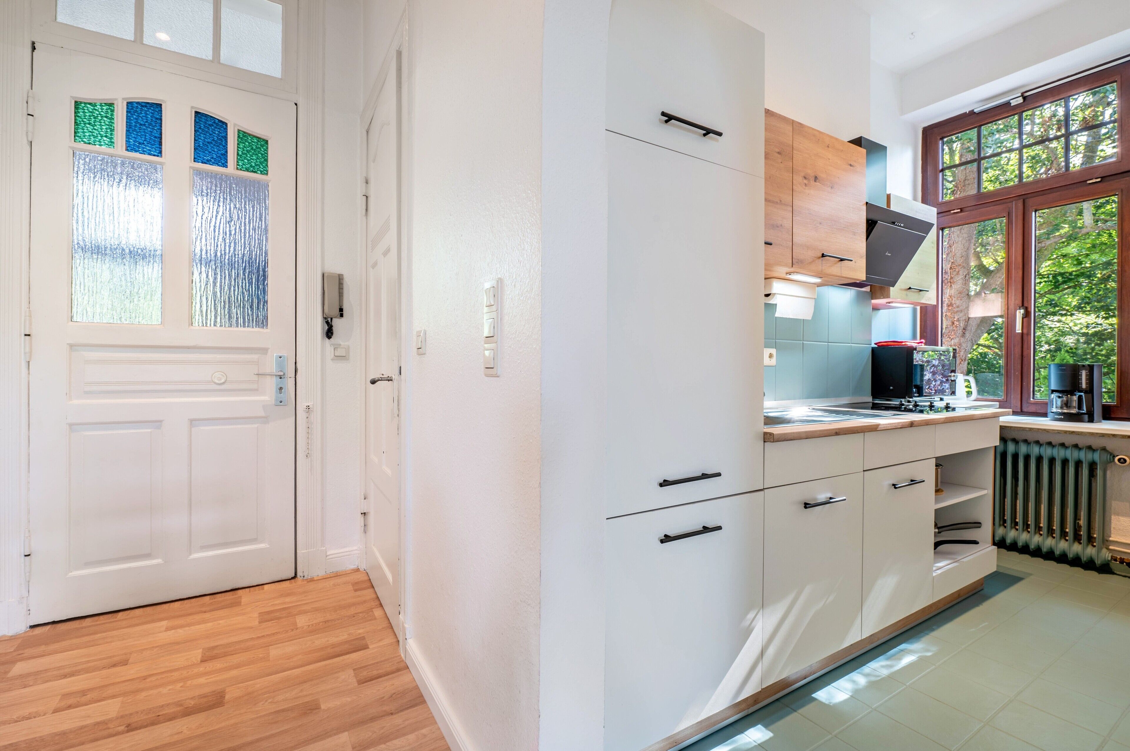 A modern kitchen with white cabinetry, a wooden countertop, and a built-in stove.
