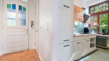 A modern kitchen with white cabinetry, a wooden countertop, and a built-in stove.