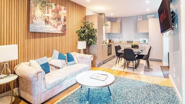 A modern living room with a sofa, a coffee table, and a dining area with chairs and a table. - 2 Bedroom City Apartment (Sheffield)