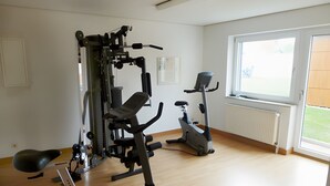 Un gimnasio con equipo de ejercicio, una ventana y un radiador.