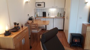 Una cocina compacta con comedor, microondas, cafetera y estufa de leña.