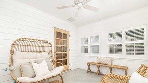 A room with a wicker chair, a bench, and a ceiling fan.