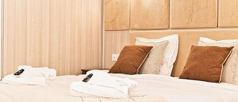 A hotel room with a large bed, two pillows, and a remote control on the bed.