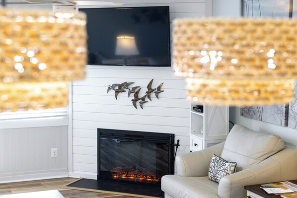 Una sala de estar con chimenea, un sofá y un televisor montado sobre la chimenea.