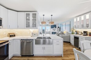 A modern kitchen with white cabinets, a central island with a sink, and a dishwasher.