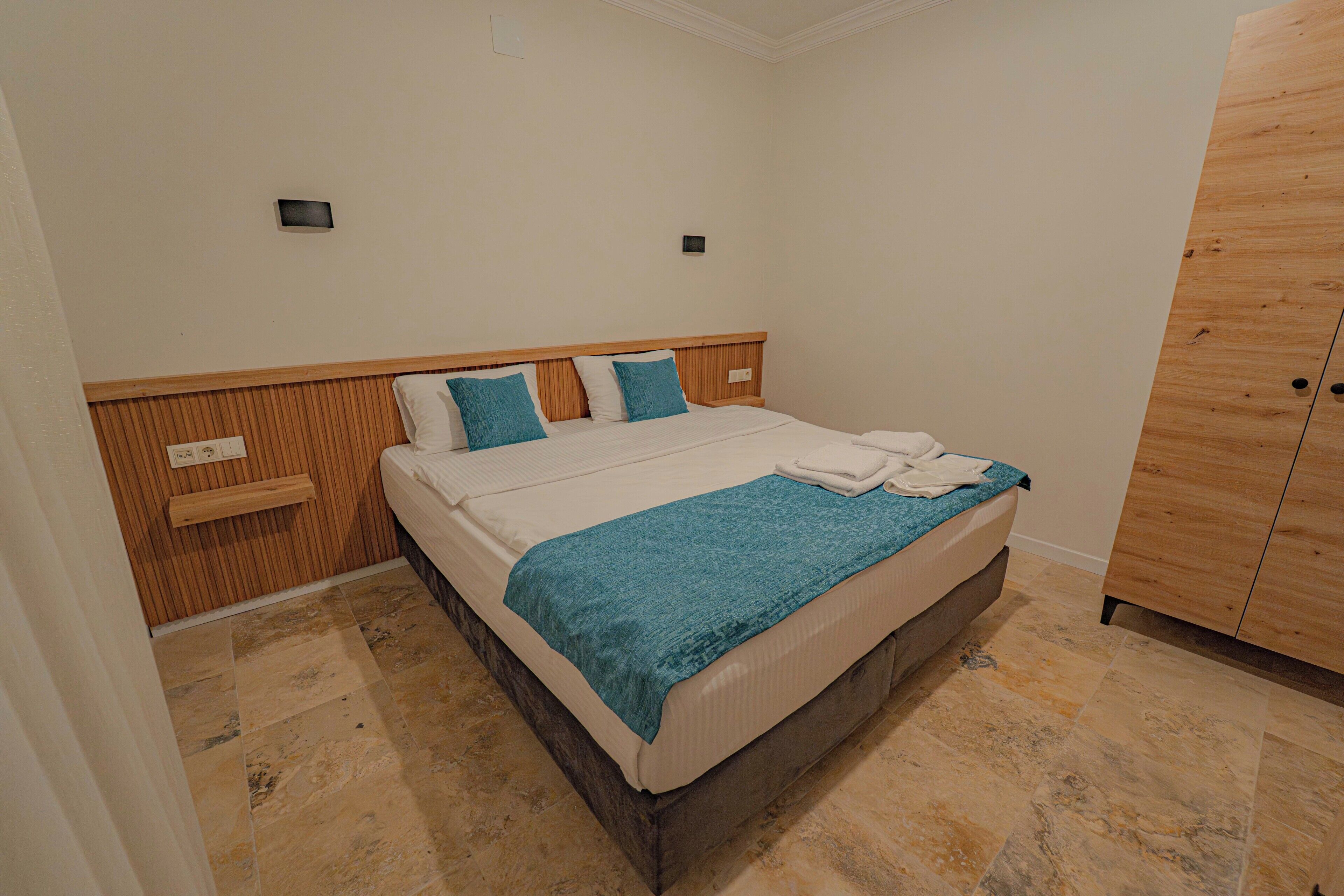 A bedroom with a bed, wooden headboard, and a wardrobe.