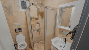 A bathroom with a toilet, a shower enclosure, a sink, and a mirror. - Full Of Life (Nevşehir)