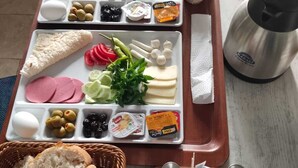 A breakfast tray with various cheeses, meats, olives, and bread, along with a coffee maker and salt shakers. - Full Of Life (Nevşehir)