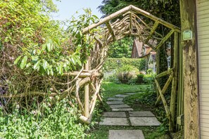 A wooden arbor over a stone pathway leading to a house. - The Granary (Southampton)