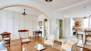 Un salon spacieux avec une table à manger en bois, des chaises en osier et une grande porte en arc donnant sur une autre pièce.