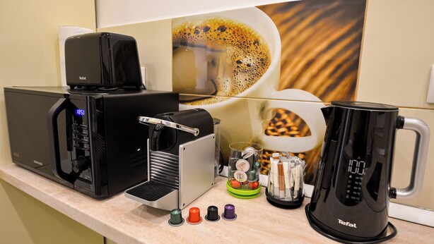 Une machine à café, une bouilloire et une tasse à café sont posés sur le plan de travail de la cuisine.