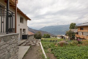 A residential building with a stone facade, a balcony, and a garden with a swing set.