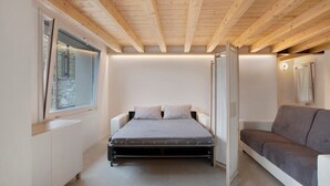 A bedroom with a bed, a sofa, a window, and a door.
