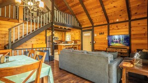 Ein Holzblockhaus-Interieur mit Essbereich, einer Couch, einem Fernseher und einer Küche.