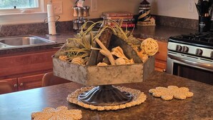 A kitchen with a marble countertop, a sink, a stove, and a decorative bowl with kitchen utensils. - Downtown Riverside Lighthouse (New Bern)