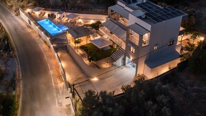 A modern multi-story house with a swimming pool, outdoor seating, and solar panels. - 3a's Family Luxury Villa (Rethymno)