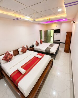 A hotel room with two beds, a flat-screen TV, a wooden wardrobe, and a mirror. - Hotel The Vintage Villa Jaisalmer (Jaisalmer)