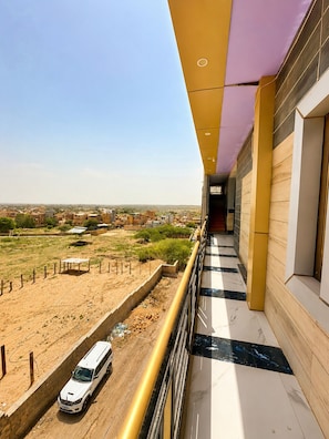 A corridor with a view of a desert landscape and a road with a white van.