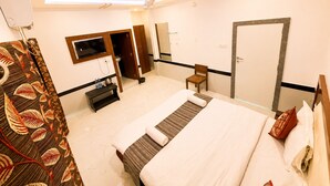 Una camera d'albergo con un letto, una televisione, un armadio, uno specchio e una porta.