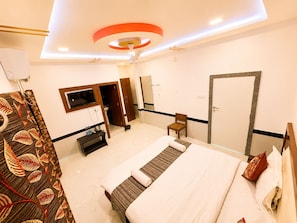 A hotel room with a bed, a television, a wardrobe, a mirror, and a door.