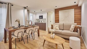 A modern living room with a wooden dining table, beige sofa, and a round coffee table. - Superb Apartment Center of Paris by Studio Prestige (Paris)
