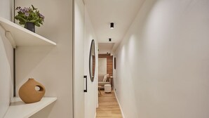 A narrow hallway with white walls, a wooden floor, and a small seating area at the end. - Superb Apartment Center of Paris by Studio Prestige (Paris)
