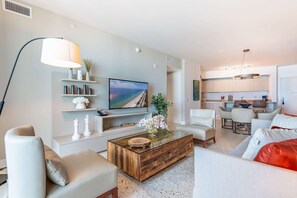 A modern living room with a flat-screen TV, a coffee table, and seating.