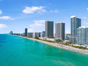 Eine Küstenstadt mit Hochhäusern, einem Strand und klarem, blauem Wasser.