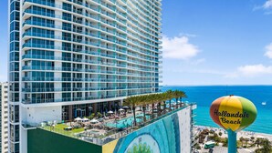 A high-rise hotel with a rooftop pool, a colorful mural, and a view of the ocean. - Roomy 2BR | Beach + Pool | Sleeps 6 (Hollywood)