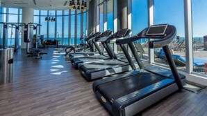 A gym with treadmills and exercise equipment, large windows, and a view of the beach. - Roomy 2BR | Beach + Pool | Sleeps 6 (Hollywood)