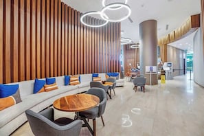 Un hall d'entrée moderne avec un mur composé de lambris en bois, des espaces de détente et un bar à café.