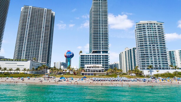 A beachfront hotel with high-rise buildings, a beach, and a clear sky. - Roomy 2BR | Beach + Pool | Sleeps 6 (Hollywood)