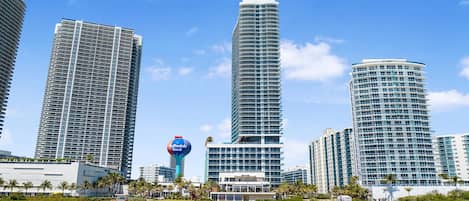 A beachfront hotel with high-rise buildings, a beach, and a clear sky.