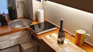 Een keuken met een roestvrijstalen spoelbak, een digitale weegschaal, een wijnfles en een mok.